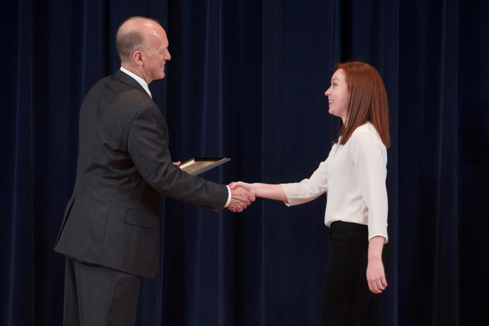 Doctor Potteiger shaking hands with an award recipient in a white shirt